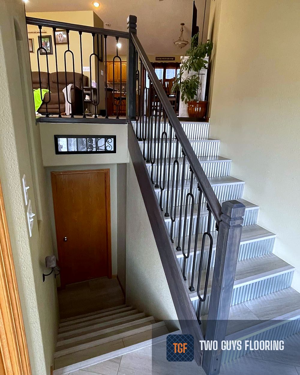 The same staircase after — porcelain tile treads, fluted risers, and a stained railing with wrought-iron balusters